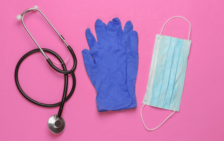 Medical gloves and mask, stethoscope on a pink background. Top viewの写真素材