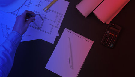 Engineering workspace. Female hands draw a building plan in neon lightの写真素材