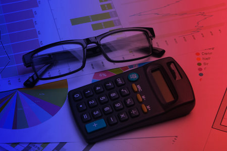 Classic eyeglasses and calculator with graphs and charts. Neon light. Economic calculation, analytics, business concept.の写真素材