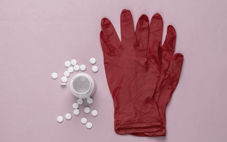 Medical gloves and bottle of pills on pink background. Top view.