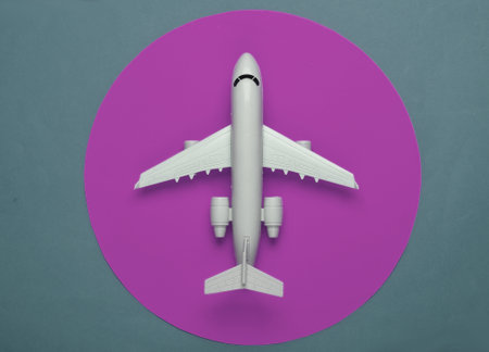 Toy model of plane on blue background with purple circle. The concept of tourism, air travel, minimalism. Top viewの写真素材