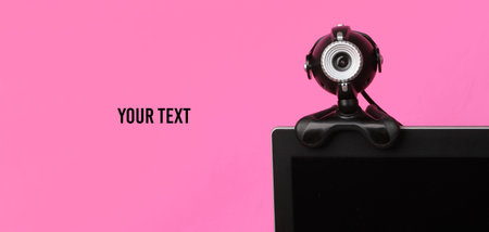 Fragment of a monitor with a web camera on pink background. Copy spaceの写真素材