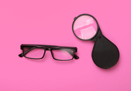 Magnifying glass and glasses on pink background. Top viewの写真素材