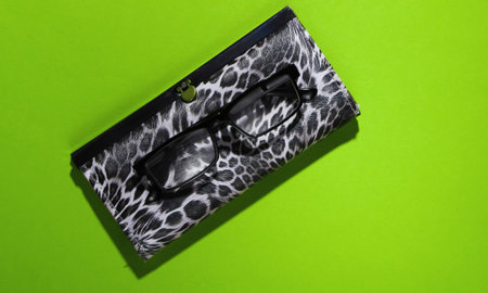 Stylish wallet and glasses on green background with shadow. Fashion minimalism. Top viewの写真素材