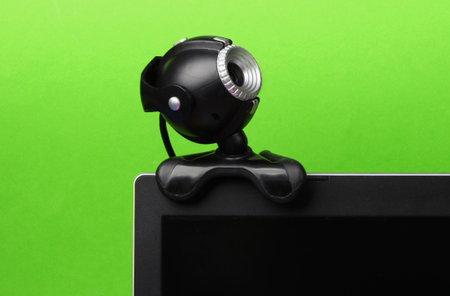 Fragment of a monitor with a web camera on green background.