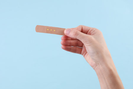 Hand holding medical plaster on blue backgroundの写真素材