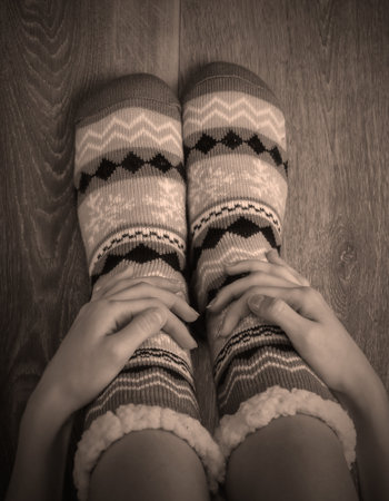 Female legs in warm cozy socks on a wooden floor in the room.の写真素材