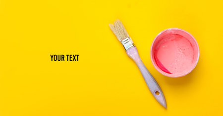 Empty can with paint and a brush on a yellow background. Pastel color trend. Top view. Copy spaceの写真素材