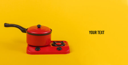 Toy plastic stove with pan on a yellow background. Kid's Kitchen. Copy spaceの写真素材