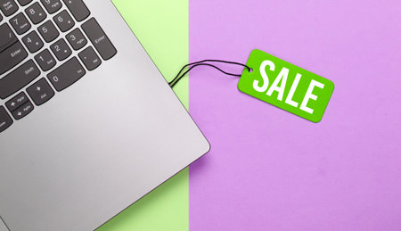Laptop with green sale tag on colored pastel background. Big Sale, discounts, online shopping. Top viewの写真素材