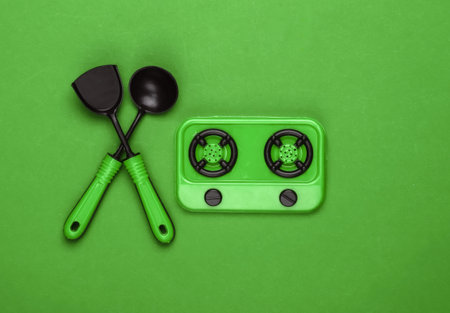 Toy stove and kitchen tools on green background. Top viewの写真素材