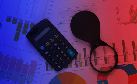 Magnifier and calculator closeup with graph and charts. Economic analysis, calculation, statistics....