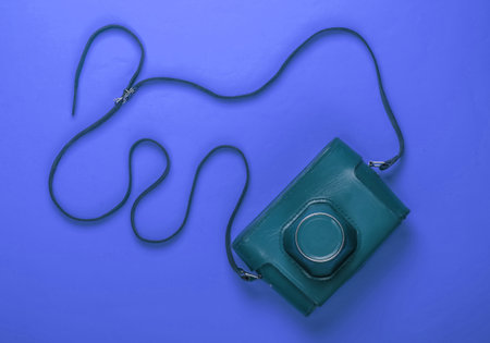 Retro camera in a leather case with strap on blue background. Top viewの写真素材