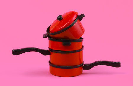Toy plastic stack of pans on pink background. Kid's Kitchenの写真素材
