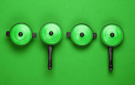 Set of toy plastic pans on green background. Top view, minimalismの写真素材