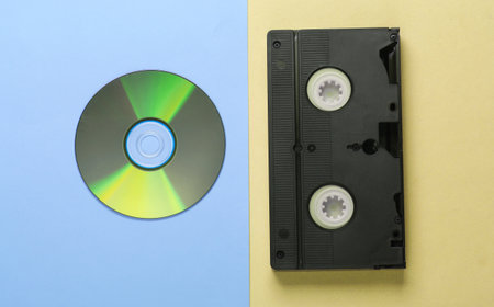 Flat lay composition of cd disc, audio cassette on yellow blue background. Retro storage media. Top viewの写真素材