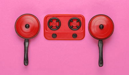 Toy plastic stove with pans on pink background. Kid's Kitchen. Top view, minimalismの写真素材