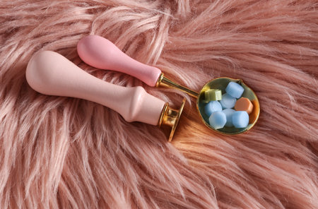 Vintage stamp and sealing wax spoon on pink fuzzy backgroundの写真素材