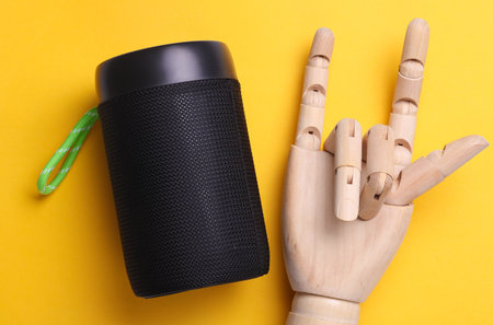 Puppet shows rock gesture and bluetooth speaker on yellow backgroundの写真素材