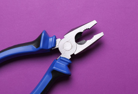 Pliers on purple background. Work, repair conceptの写真素材