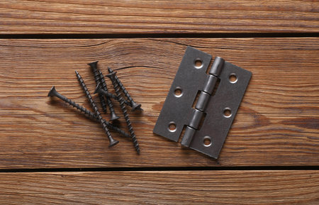 Metal door hinges with screws on wooden backgroundの写真素材
