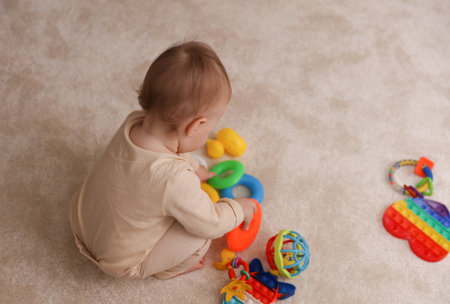 Little cute baby playing with toys sitting on the carpet