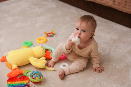 Little cute baby playing with toys sitting on the carpetの写真素材