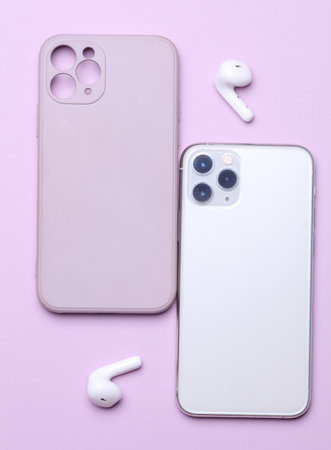 Modern smartphone with protective case and wireless earphones on purple background. Top viewの写真素材