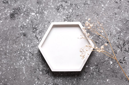 Plaster tray for candle on gray concrete background with dry grass. Creative layoutの写真素材