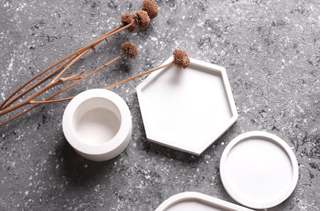 Plaster trays for candles on gray concrete background with dry grass. Creative layoutの写真素材