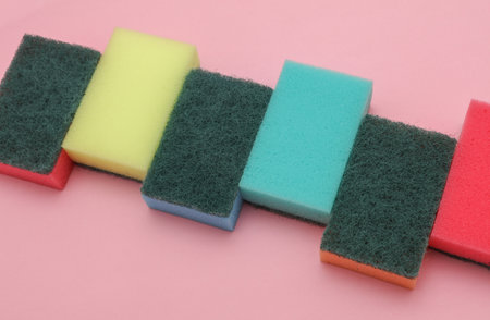 Set of colored cleaning sponges on a pink background
