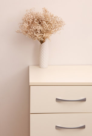 Vase with dry grass standing on a dresser