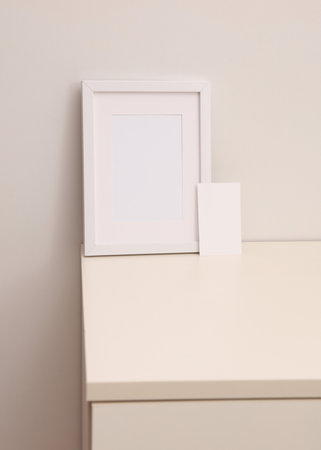 Mockup of a white empty photo frame and business card standing on a dresserの写真素材
