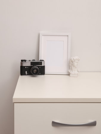 Mockup of a white empty photo frame and decor standing on a dresserの写真素材