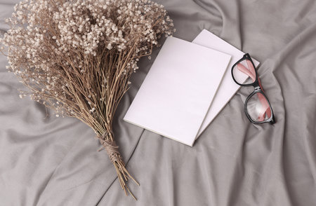 Two books with white covers on a sheet of bed with dry grass