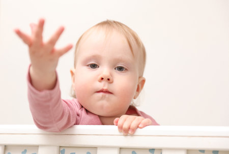 Portrait of cute baby in crib with bumper