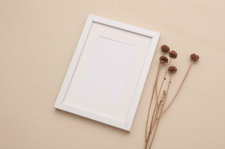 Mockup of white photo frame with dry grass on beige background