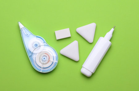 Correctors and erasers on a green background. Stationery school suppliesの写真素材
