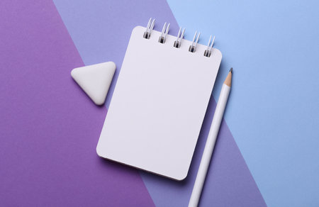 Notebook with pencil and eraser on purple background