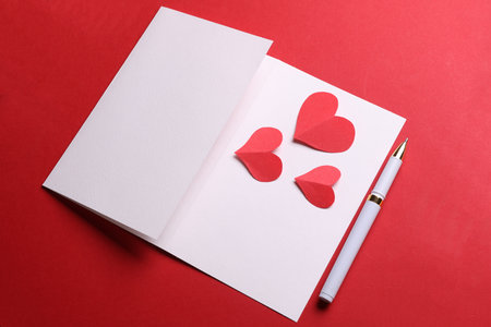 White Invitation card mockup or valentine with paper hearts on red background. Love concept. Top...
