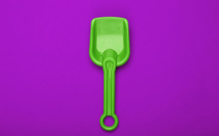 Children's green shovel for a sandbox or beach on purple background. Top viewの写真素材