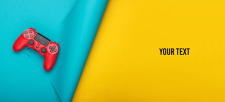 Red gamepad on blue yellow background. Copy space. Gaming, leisure and entertainment concept. Top...