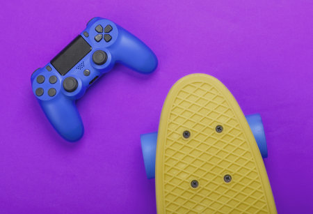 Gamepad with cruiser board on purple background. Childhood concept, summer fun. Top view. Flat layの写真素材