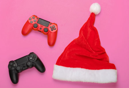 Gamepads with santa hat on pink background. Top view