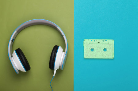 Stereo headphones with audio cassette on green blue background. Music lover. Retro 80s. Top view.の写真素材