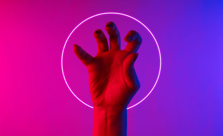 Halloween concept. Female hand with scary gestures. Neon blue-pink gradient light with circle. Night...