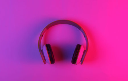 Modern stereo wireless headphones with neon pink blue light. Gradient glow. Top view