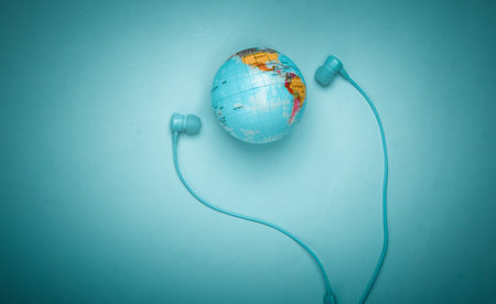 World song. Global music chart. The music of earth. Stereo earphones and a globe on a blue background. Top viewの写真素材