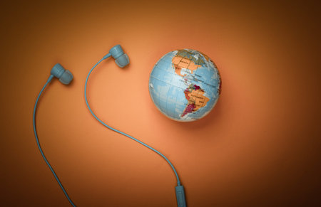 World song. Global music chart. The music of earth. Stereo earphones and a globe on yellow...