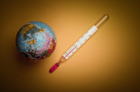 Global warming still life. Globe and thermometer on a yellow background. Global climate issues. Eco conceptの写真素材
